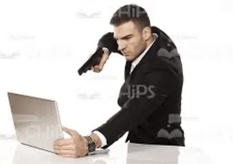 A main in a suit points a gun at his computer.